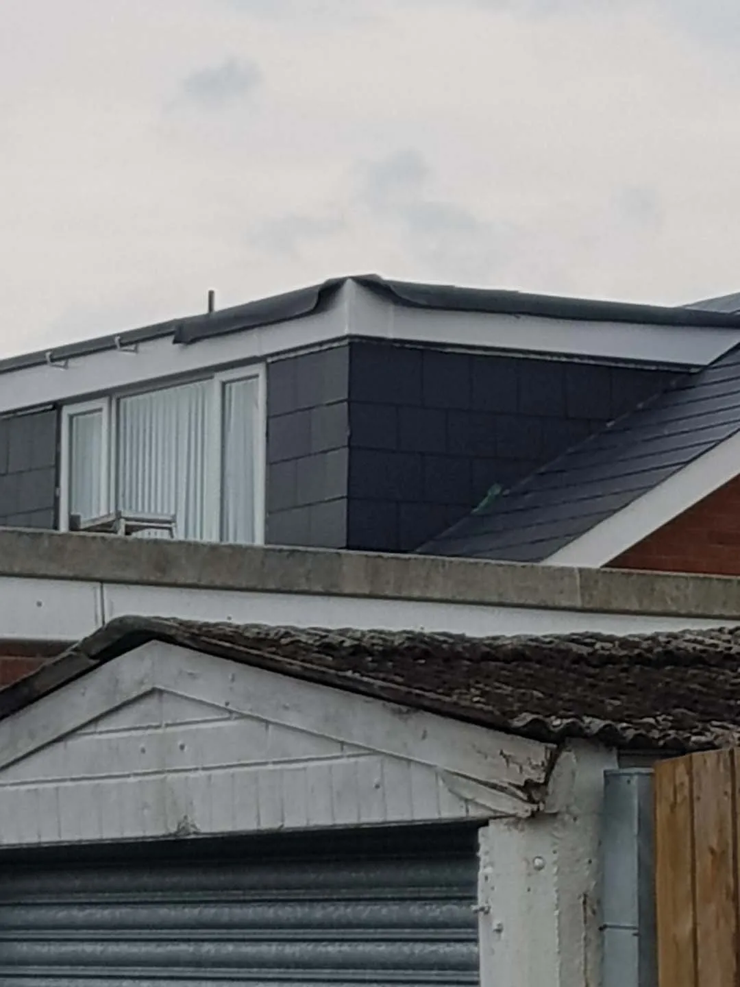 Dormer with new dark cladding and flat-roof edge being finished