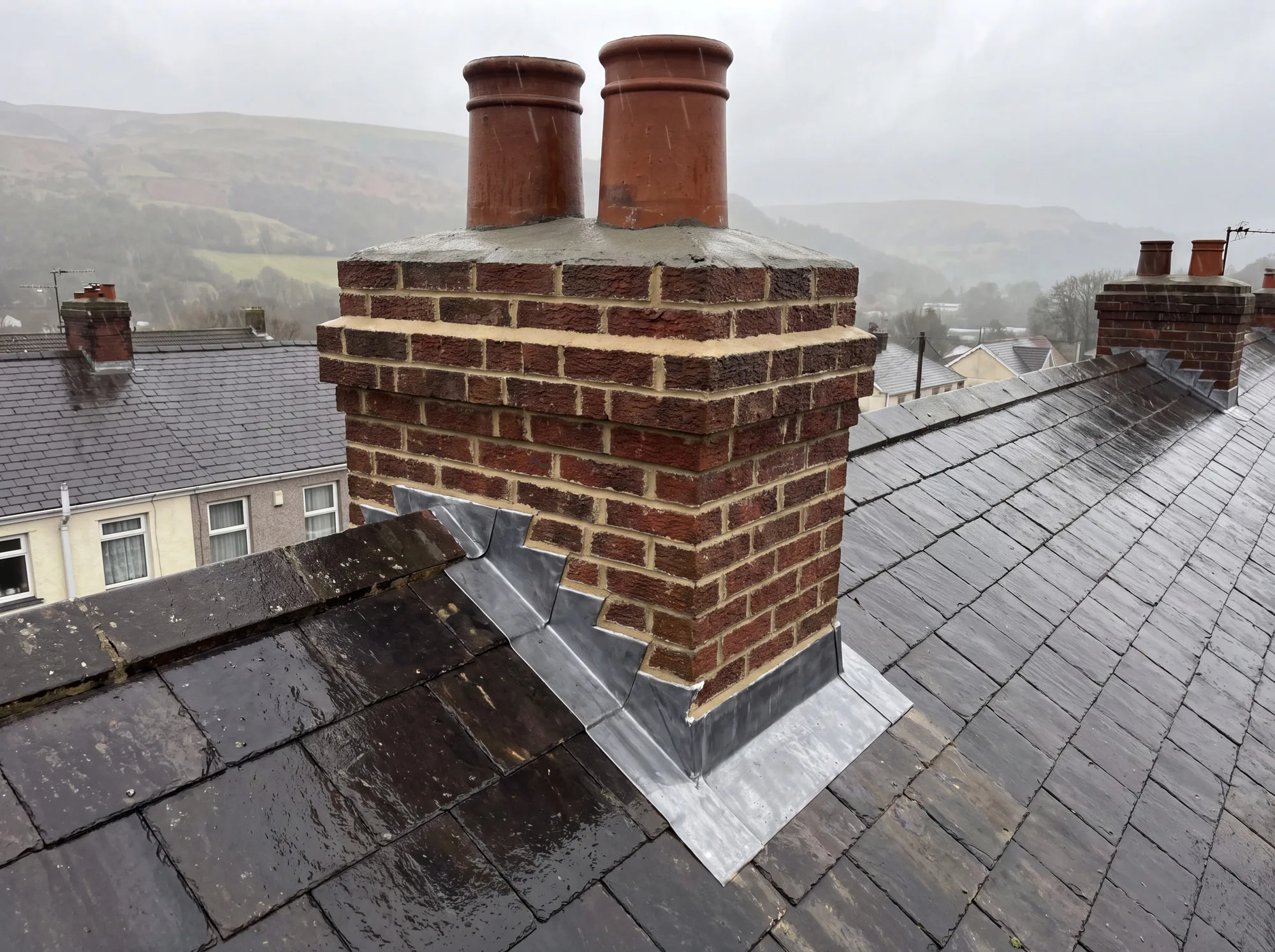 A repointed brick chimney stack with new lead flashing dressed into the roof