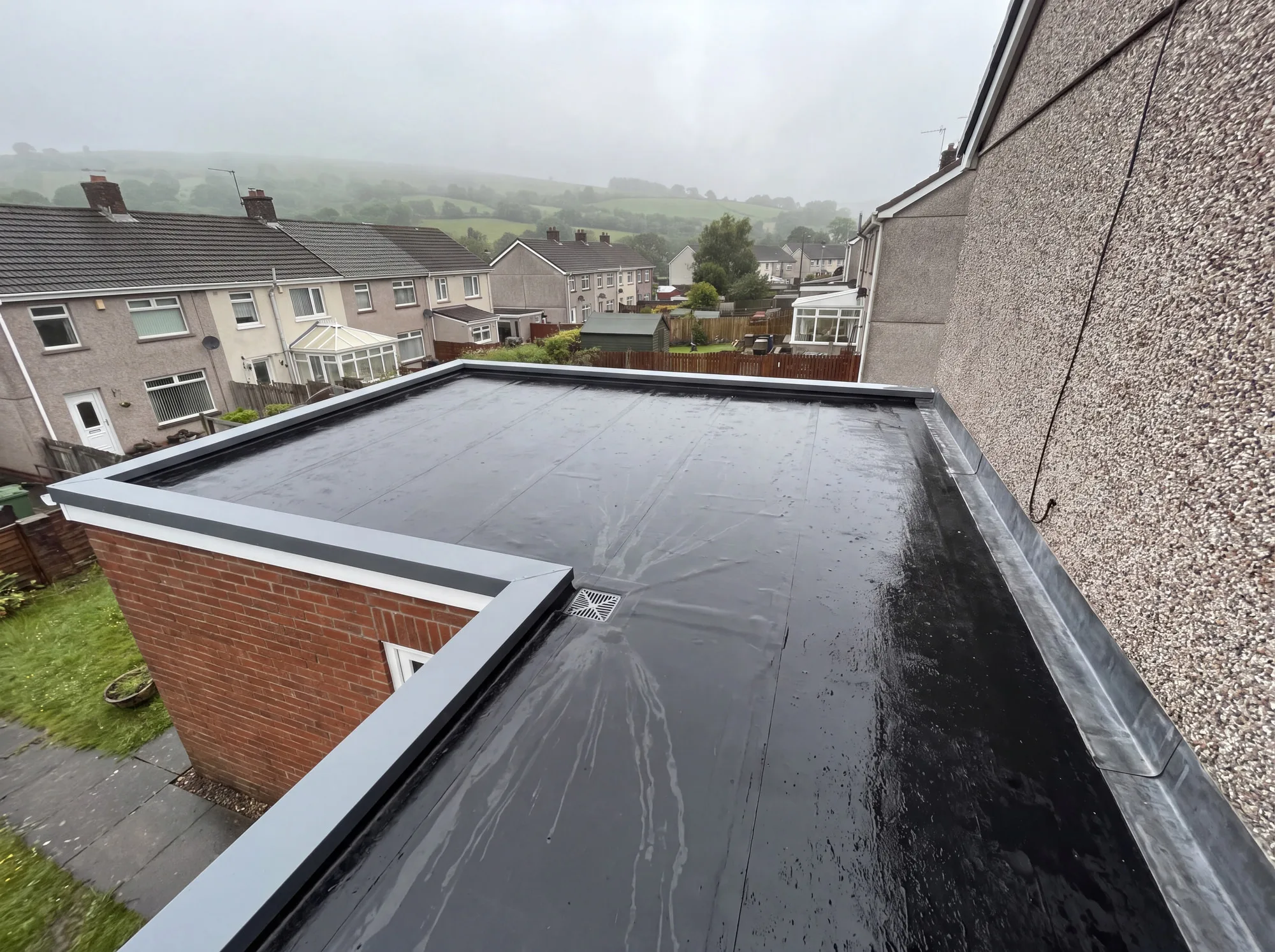 A newly laid black EPDM rubber flat roof over a single-storey extension