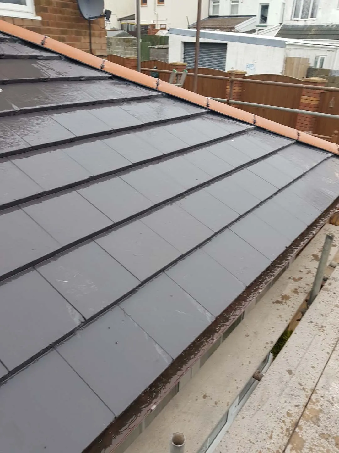 Slate-effect tiled roof slope with a clay hip line and new gutter