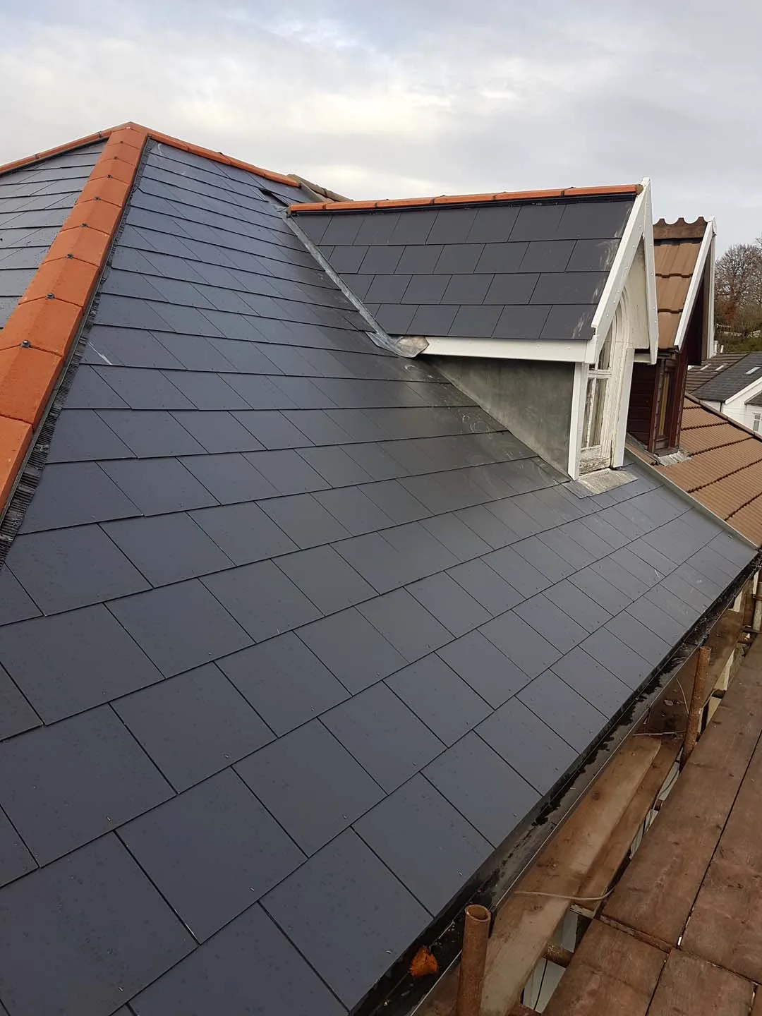 Slate roof with red clay hip tiles and a lead valley running down beside a gable dormer