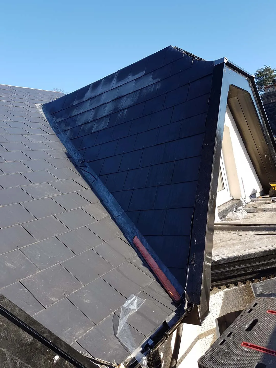Slate-hung dormer cheek with lead valley and black fascia on a new slate roof