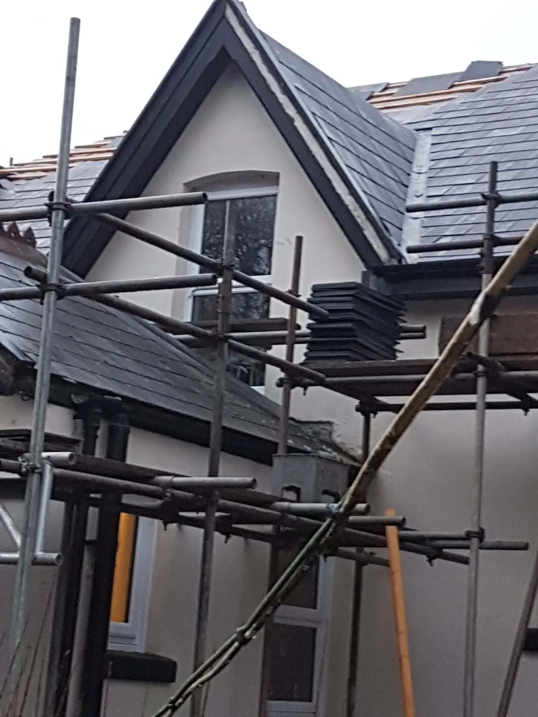 Scaffolding around a steep period gable with stacks of slates ready on the scaffold