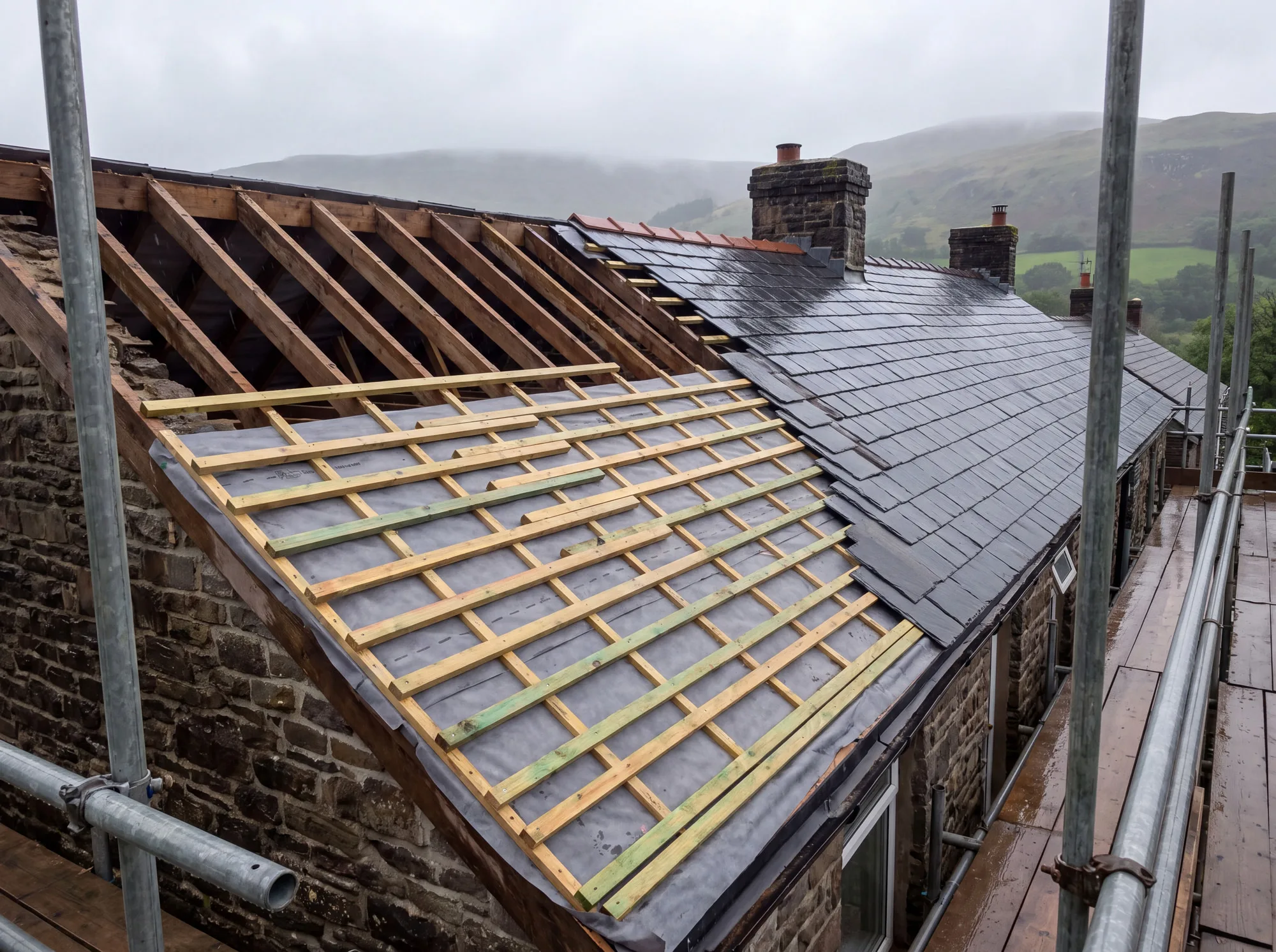 A roof part-stripped to the rafters with new battens and membrane, part re-covered in slate